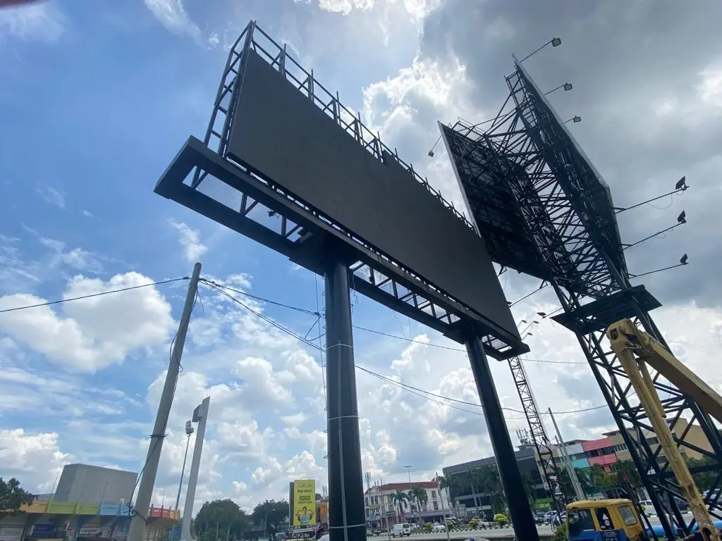 Outdoor LED billboard installation site in Malaysia with a crane beside the elevated screen