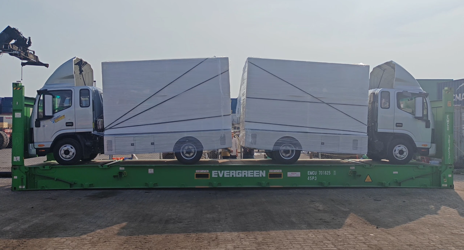Two mobile LED advertising trucks wrapped for protection and loaded onto a flat rack container for shipping